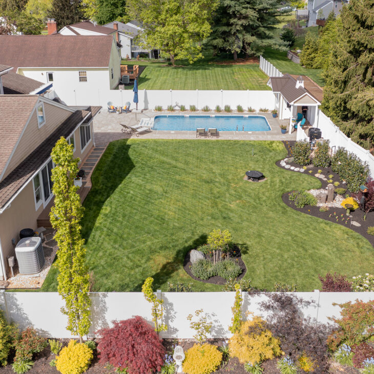A beautiful aerial view of a rectangular, fenced-in yard with a pool.